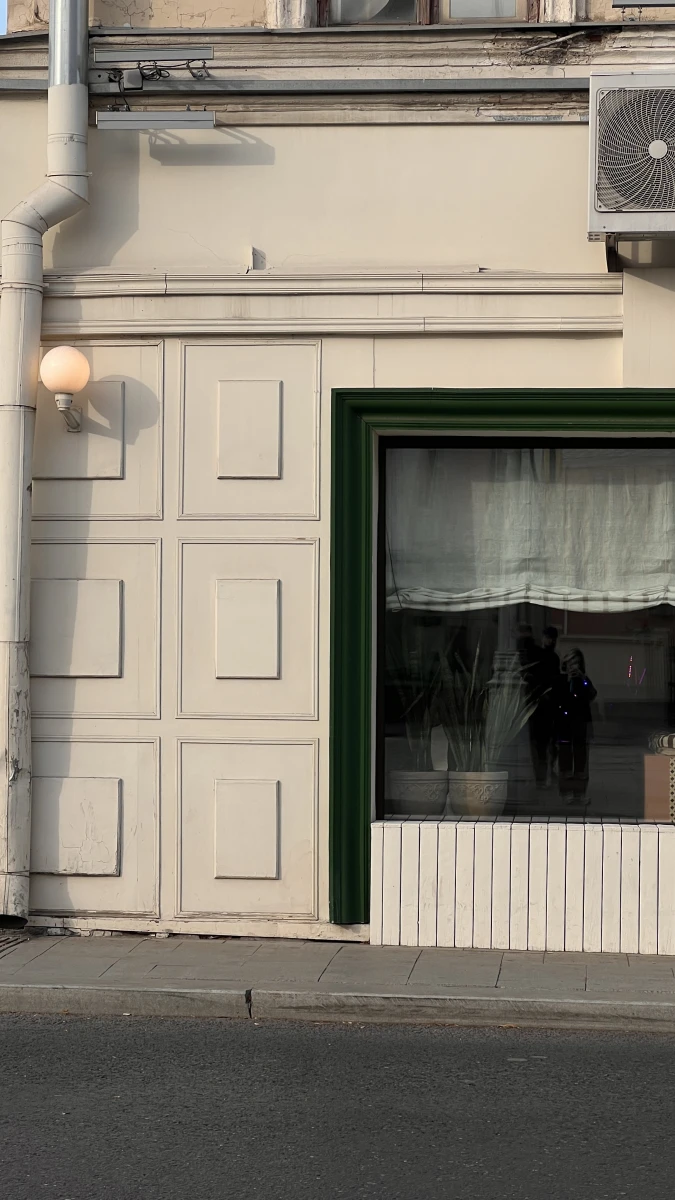 Белый фасад здания с большим зеленым окном