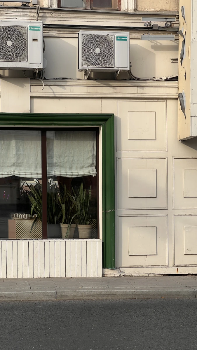 Белый фасад здания с большим зеленым окном