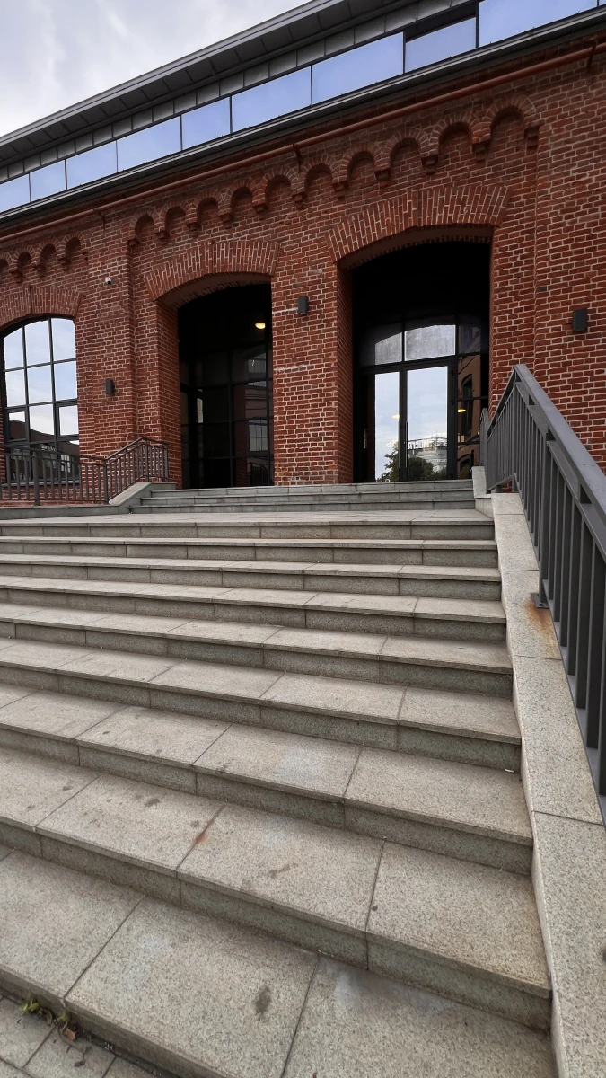 Красивая лестница на фоне фасада из красного кирпича