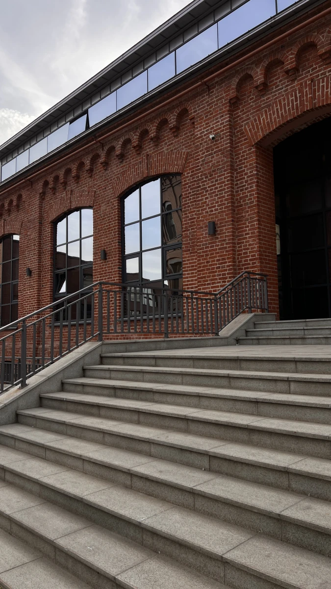 Красивая лестница на фоне фасада из красного кирпича