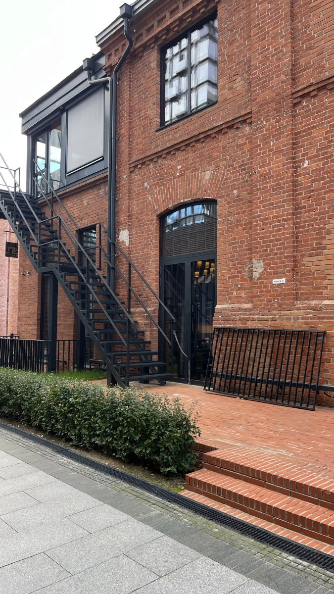Красное кирпичное здание, трубы и лестница