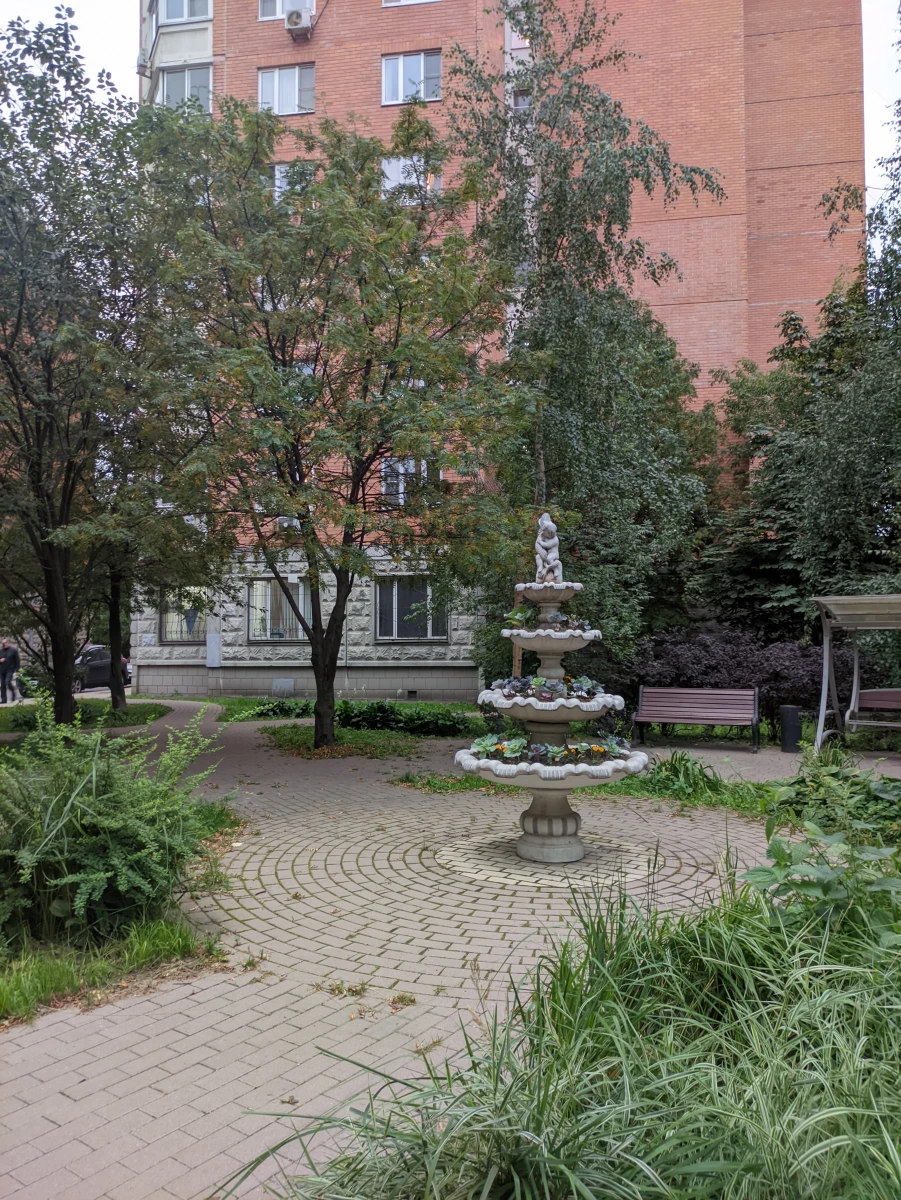 Уютный дворик с качелями и скульптурой-фонтаном